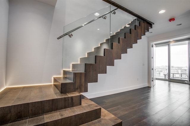 staircase featuring recessed lighting, hardwood / wood-style floors, and baseboards