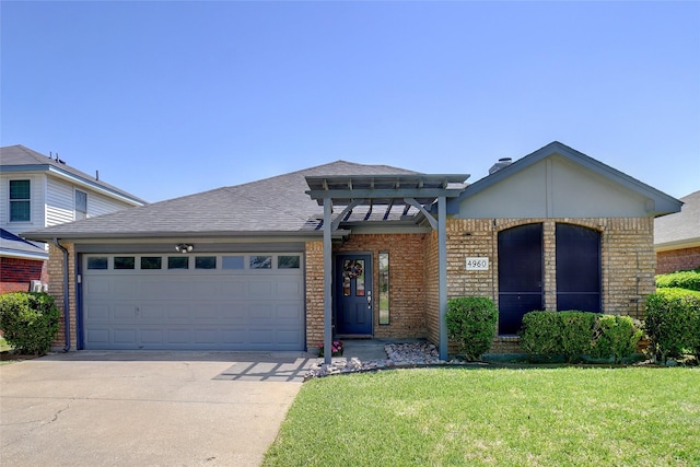 prairie-style home with roof with shingles, concrete driveway, an attached garage, brick siding, and a front yard