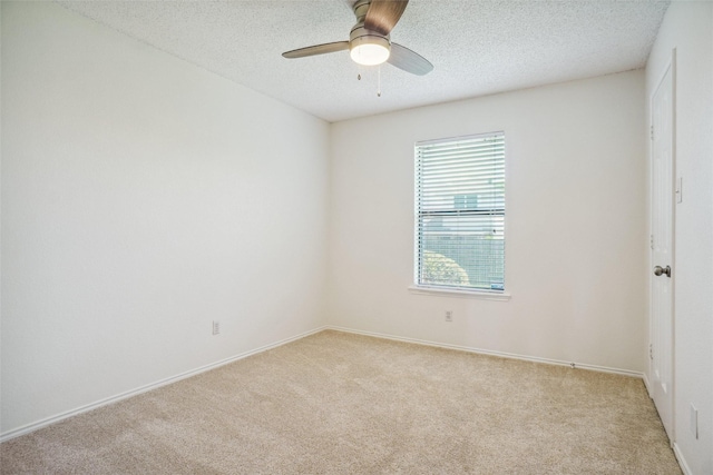 spare room with ceiling fan, light carpet, a textured ceiling, and baseboards