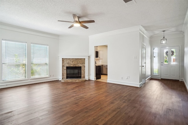 unfurnished living room featuring dark wood-type flooring, a wealth of natural light, a ceiling fan, and ornamental molding