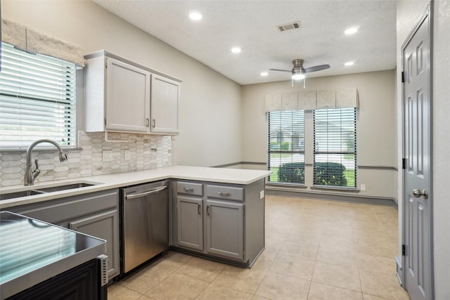 kitchen featuring dishwasher, visible vents, a sink, gray cabinetry, and a peninsula