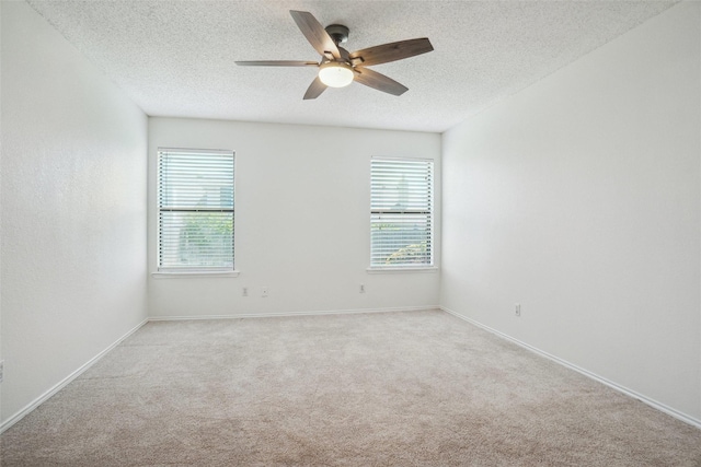 unfurnished room with a textured ceiling, a ceiling fan, light carpet, and a healthy amount of sunlight