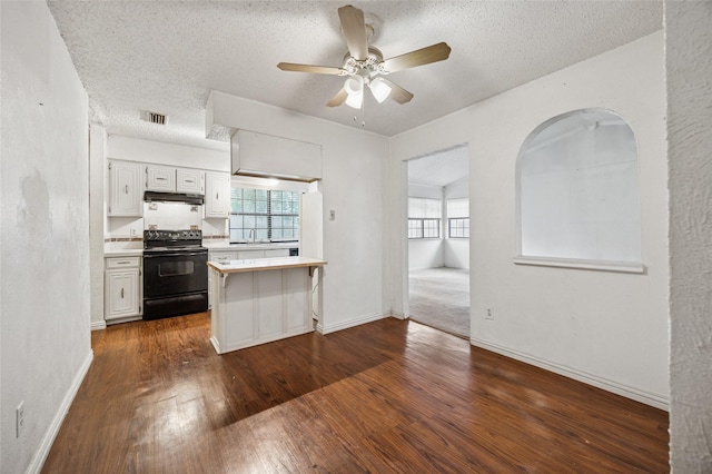 kitchen with dark wood-style flooring, visible vents, black electric range oven, light countertops, and under cabinet range hood