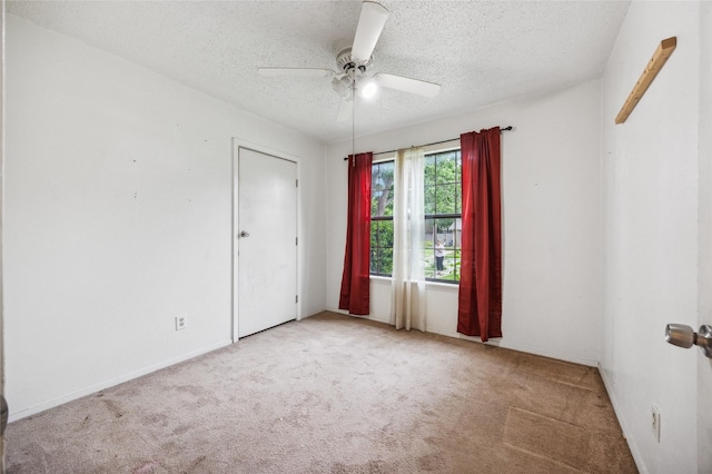 unfurnished room with a ceiling fan, a textured ceiling, baseboards, and carpet
