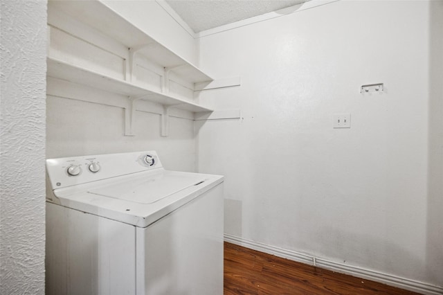 clothes washing area with dark wood-style flooring, laundry area, washer / dryer, and baseboards