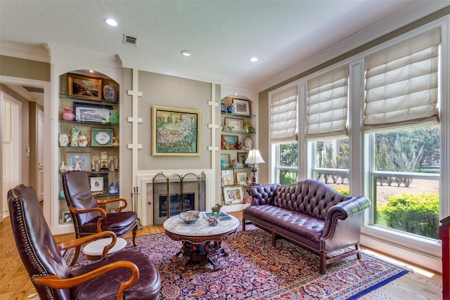 6001 Laurel Valley Ct, Fort Worth, TX 76132 - living room featuring wood finished floors, ornamental molding, built in shelves, a glass covered fireplace, and a textured ceiling