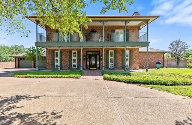 view of front of home with a porch, fence, a balcony, and brick siding