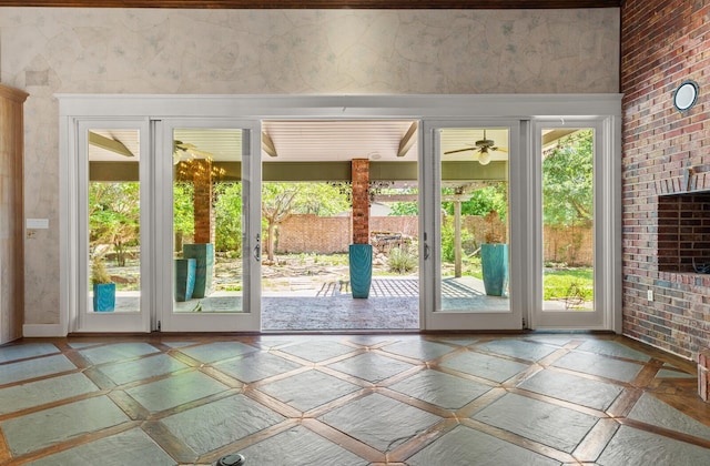doorway to outside featuring ceiling fan, a healthy amount of sunlight, and brick wall