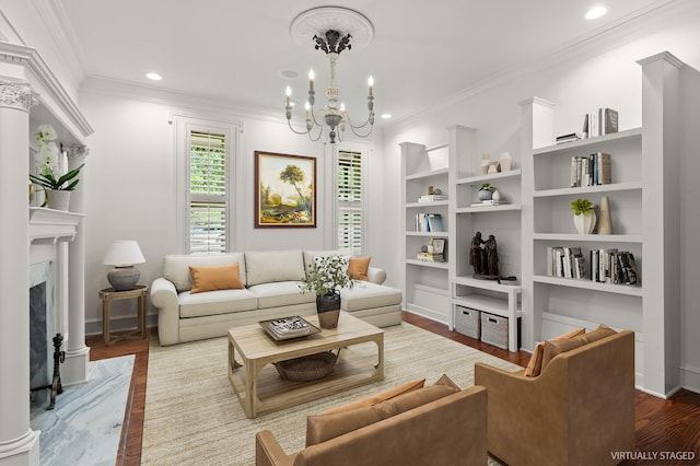living room with a chandelier, a high end fireplace, wood finished floors, and crown molding