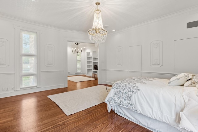 bedroom with a chandelier, wood finished floors, crown molding, and multiple windows