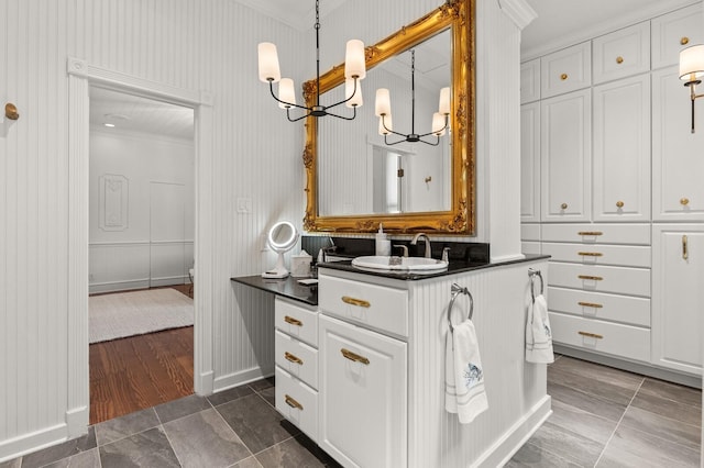 bathroom with baseboards, a notable chandelier, tile patterned flooring, vanity, and ornamental molding