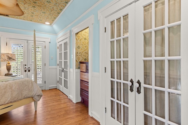 bedroom with wood finished floors, a wainscoted wall, access to outside, and french doors