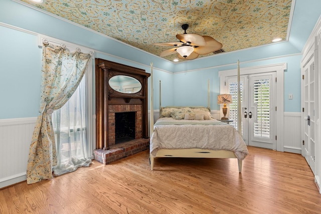bedroom featuring wainscoting, wood finished floors, access to outside, and ornamental molding