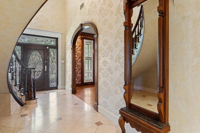 tiled foyer entrance with arched walkways, visible vents, and baseboards