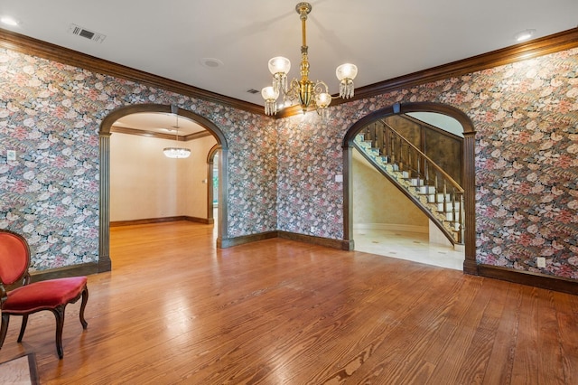 unfurnished dining area featuring wallpapered walls, visible vents, arched walkways, and a notable chandelier