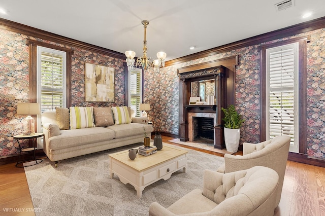 living area featuring ornamental molding, a chandelier, visible vents, and light wood-style flooring