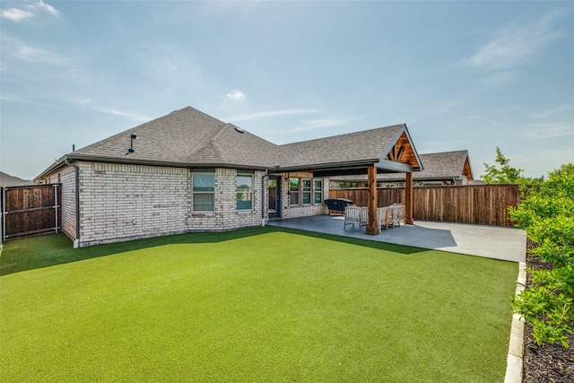 rear view of house featuring brick siding, roof with shingles, a fenced backyard, and a patio