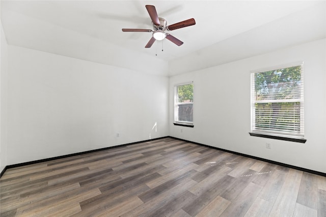 spare room with wood finished floors, a ceiling fan, and baseboards