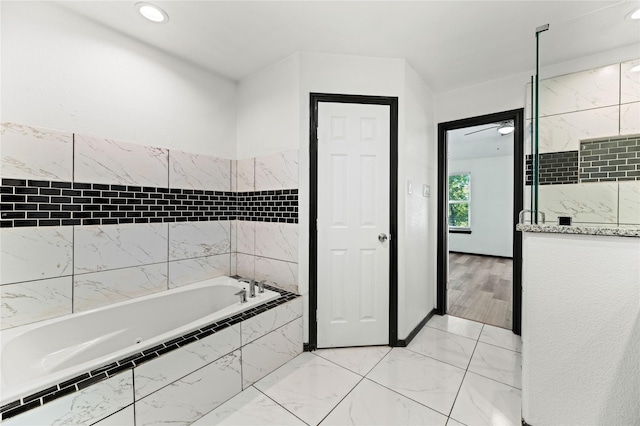 full bath featuring marble finish floor, tiled tub, and recessed lighting