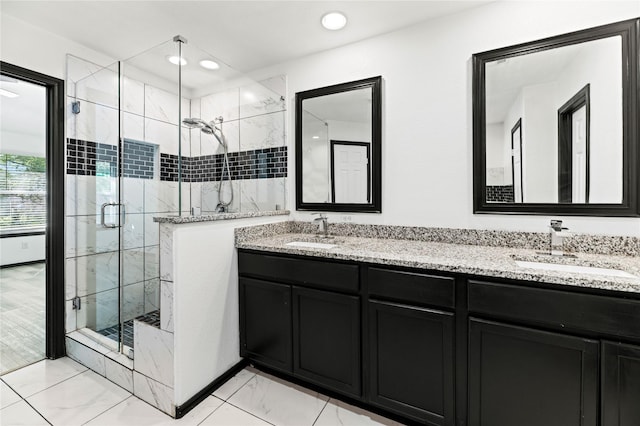 full bath with marble finish floor, a sink, a marble finish shower, and double vanity