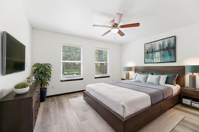 bedroom with light wood-style flooring, baseboards, and ceiling fan