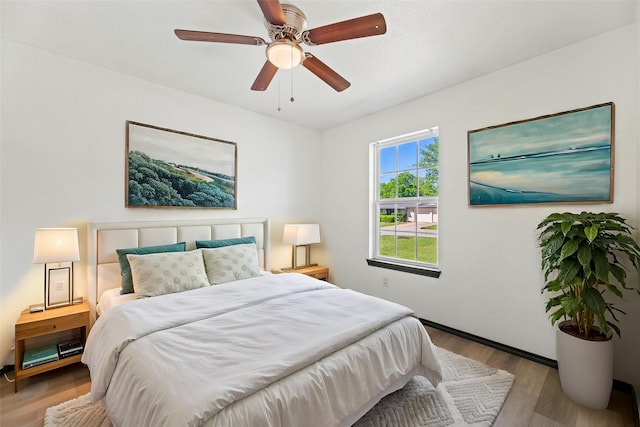 bedroom featuring light wood-type flooring, a ceiling fan, and baseboards