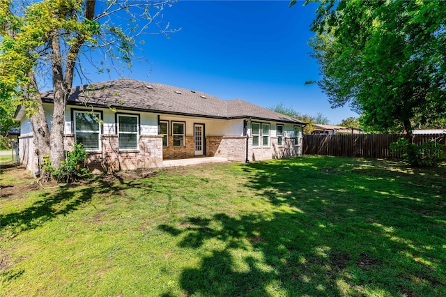 back of house with brick siding, a patio area, a lawn, and fence