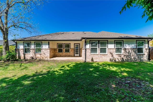 back of property featuring brick siding, a lawn, and a patio