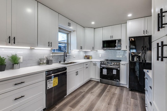 kitchen featuring light countertops, white cabinetry, a sink, and black appliances