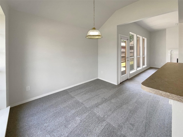 unfurnished dining area featuring dark carpet, baseboards, and vaulted ceiling