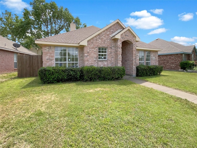 ranch-style home featuring a front lawn, a chimney, fence, brick siding, and a shingled roof