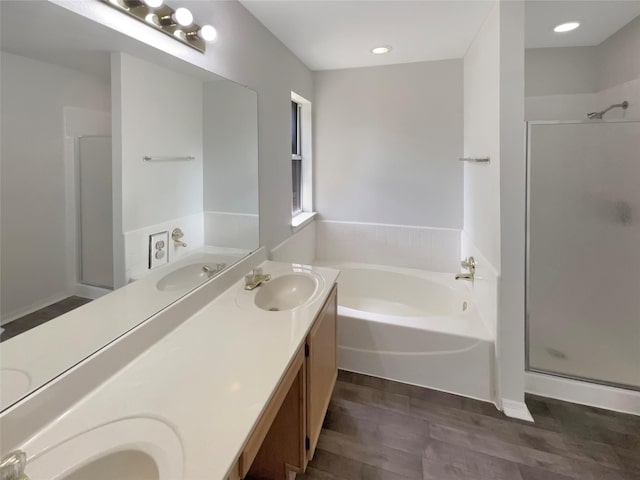 bathroom featuring double vanity, a bath, a stall shower, and a sink