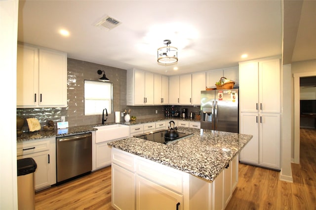 kitchen with light wood-type flooring, decorative backsplash, visible vents, and appliances with stainless steel finishes