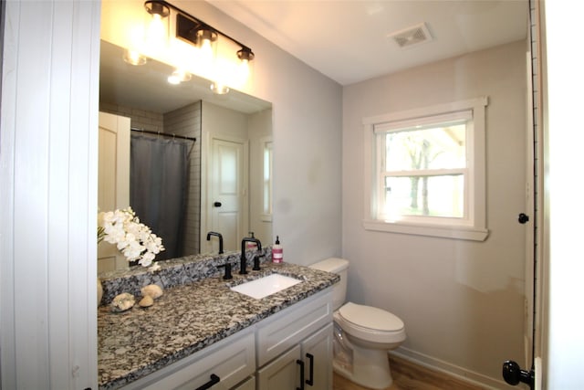 bathroom with toilet, baseboards, visible vents, wood finished floors, and vanity