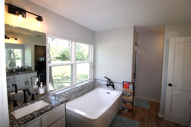 full bathroom with wood finished floors, a freestanding tub, vanity, and a wealth of natural light