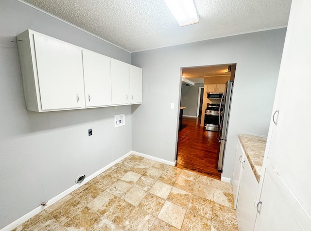laundry area with a textured ceiling, electric dryer hookup, cabinet space, baseboards, and washer hookup