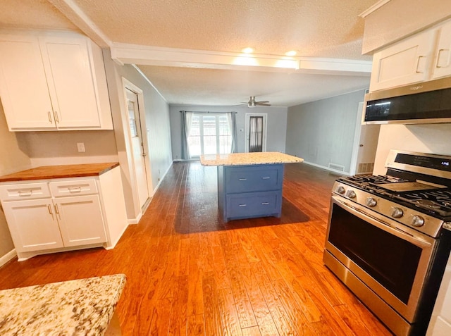 kitchen featuring a textured ceiling, ceiling fan, stainless steel appliances, light wood finished floors, and white cabinets