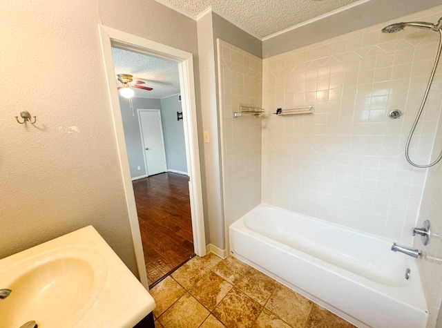 bathroom with a ceiling fan, shower / bathtub combination, a textured ceiling, and a sink