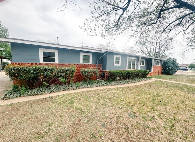 ranch-style house featuring brick siding and a front yard