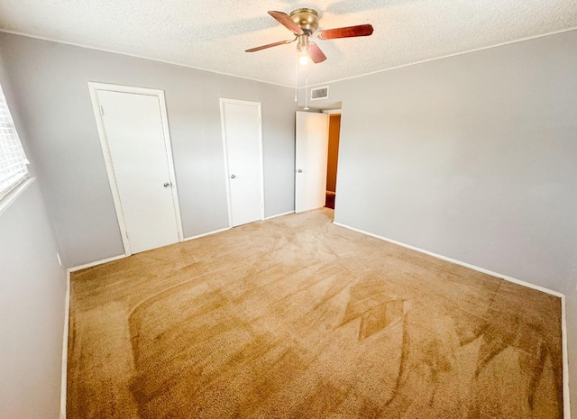 unfurnished bedroom with carpet floors, visible vents, a textured ceiling, and ceiling fan