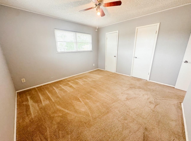 unfurnished bedroom with carpet, baseboards, a textured ceiling, and ceiling fan