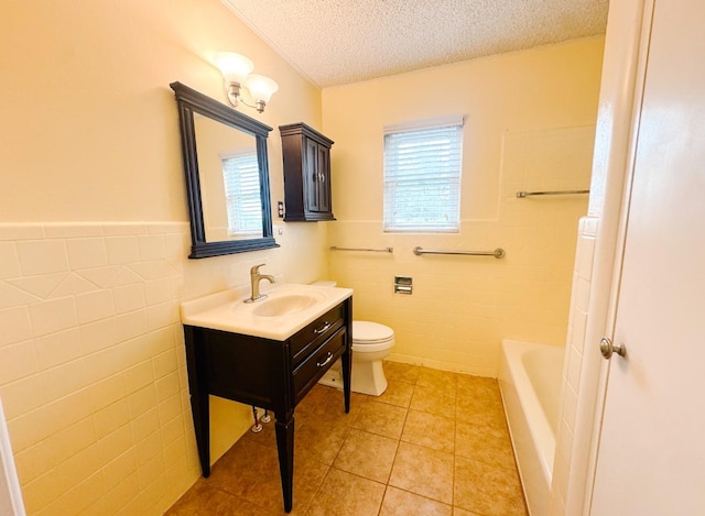 bathroom with toilet, vanity, tile walls, a textured ceiling, and a tub