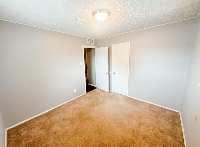 carpeted spare room with baseboards, a textured ceiling, and visible vents