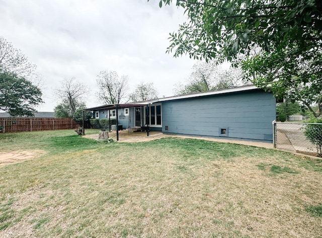 rear view of house featuring a fenced backyard, a yard, and a patio