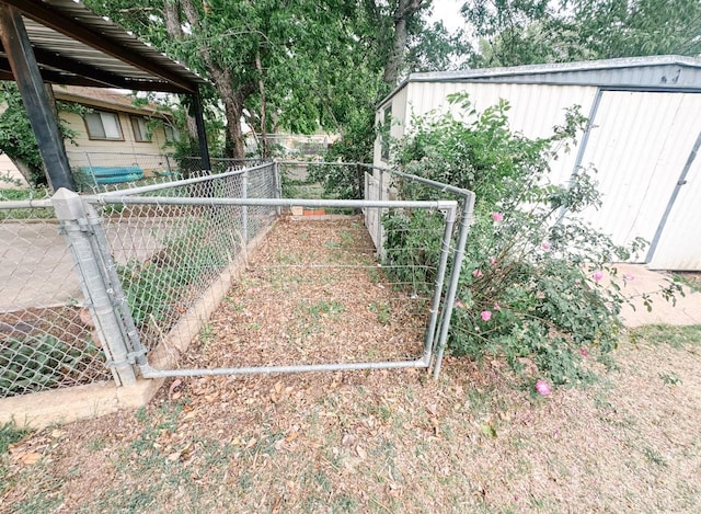 view of gate featuring fence, an outbuilding, and a shed