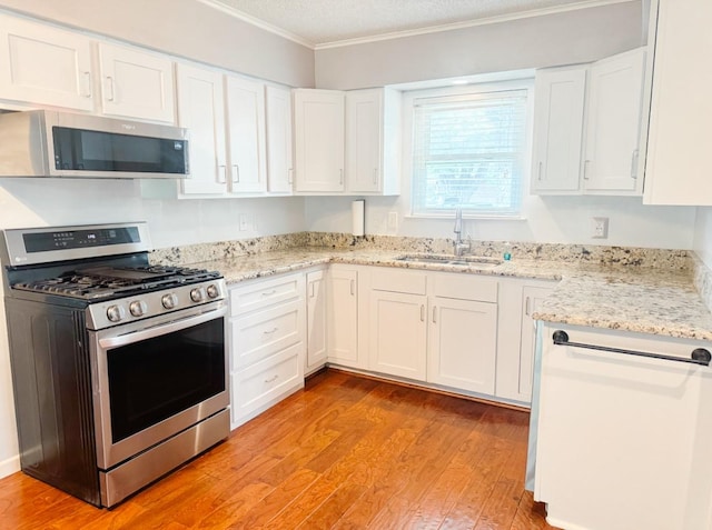 kitchen featuring white cabinets, stainless steel appliances, a sink, and ornamental molding