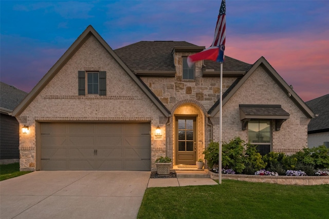 view of front of house with brick siding, concrete driveway, stone siding, a yard, and roof with shingles