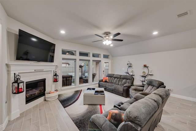 living room with a ceiling fan, wood tiled floor, a high end fireplace, baseboards, and visible vents