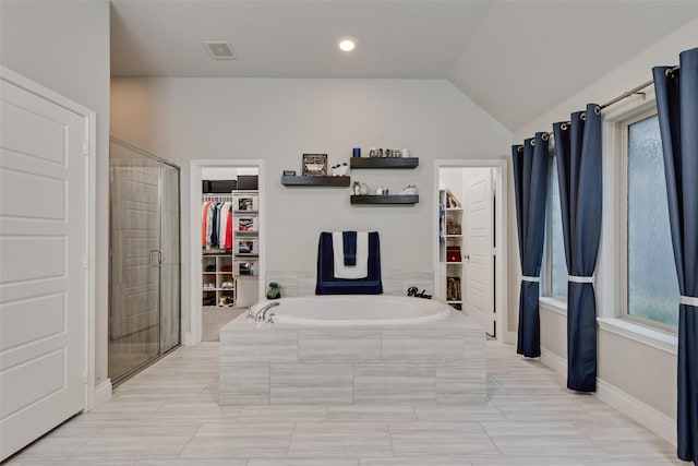 bathroom featuring recessed lighting, a shower stall, vaulted ceiling, a walk in closet, and a bath