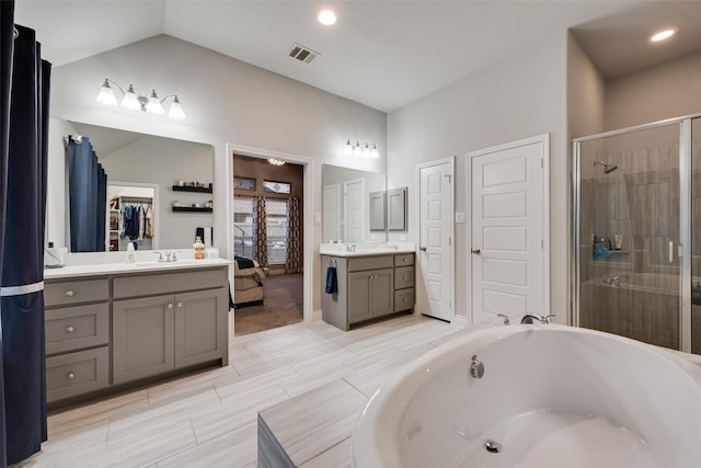full bathroom with lofted ceiling, visible vents, a washtub, two vanities, and a stall shower